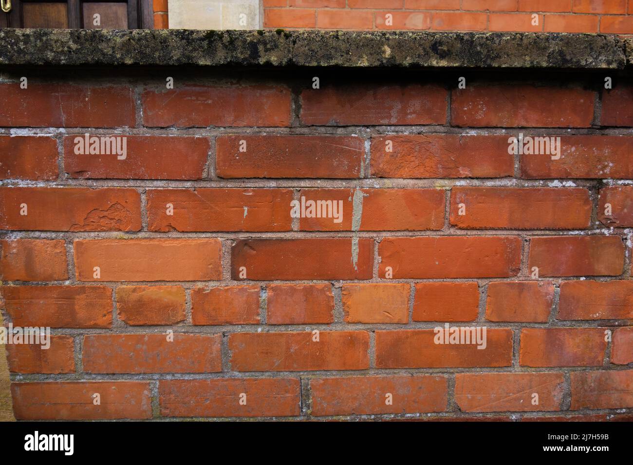 modern textured dark red brick wall with stains and cement tops to the