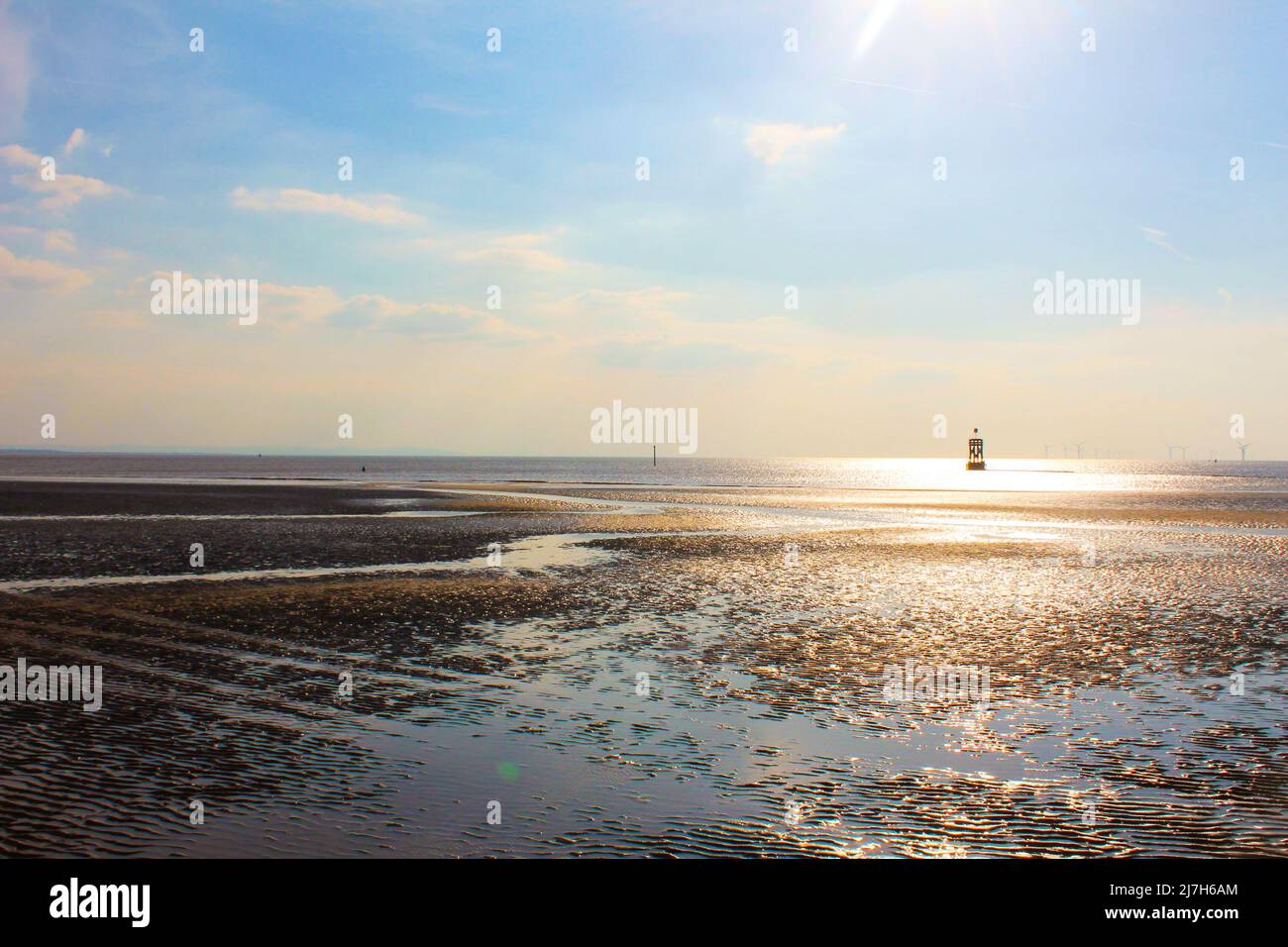 Beautiful views of Crosby Beach with low tide and sun shining on wet sand in Liverpool, England Stock Photo