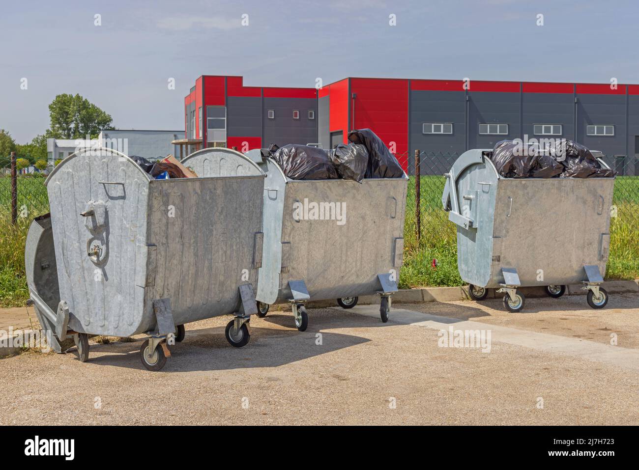 Three Metal Dumpster Bins Open Lid Overloaded With Garbage Bags Stock