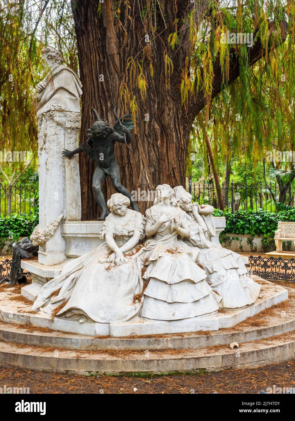 Sculptural group by Lorenzo Coullaut Valera in the  Gustavo Adolfo Bécquer turnaround. The bust of the poet, three female figures seated on a bench symbolizing the three states of love: 'excited love', 'possessed love' and 'lost love', and the bronze statue of Cupid representing 'the love that hurts - Maria Luisa park - Seville, Spain Stock Photo