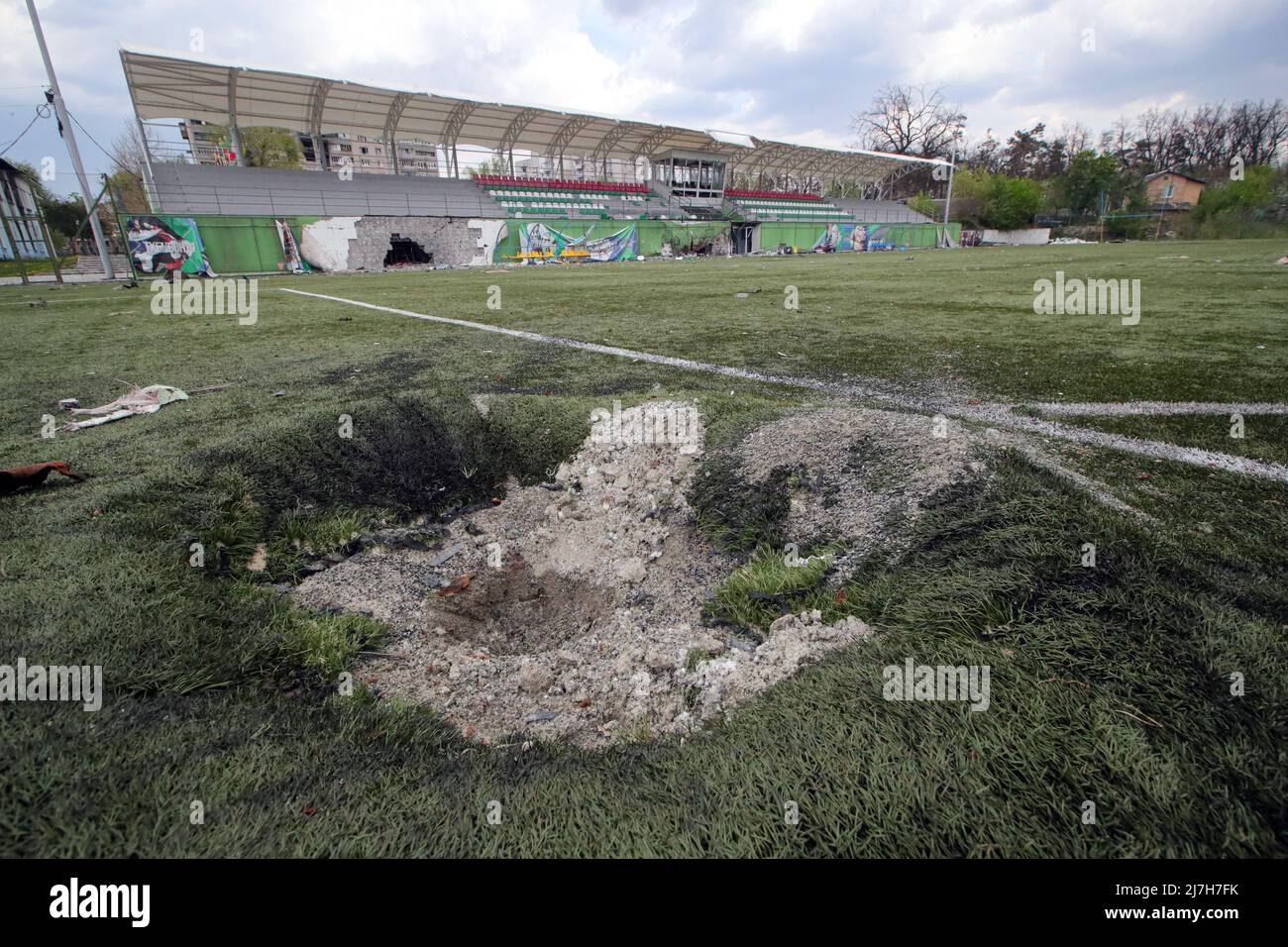 IRPIN, UKRAINE - MAY 8, 2022 -  A crater is pictured on the pitch at the Chempion Stadium damaged as a result of Russian shelling in Irpin, Kyiv Regio Stock Photo