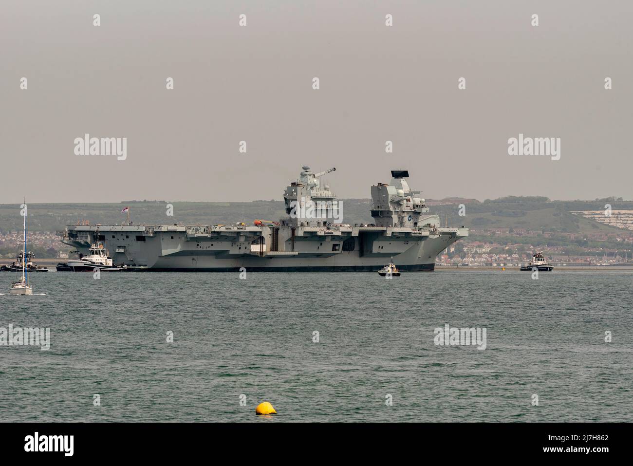 Port Portsmouth, Hampshire, England, UK. 2022. Tugs in attendace to rotate the aircraft carrier HMS Prince Charles in Portsmouth Harbour UK. Stock Photo