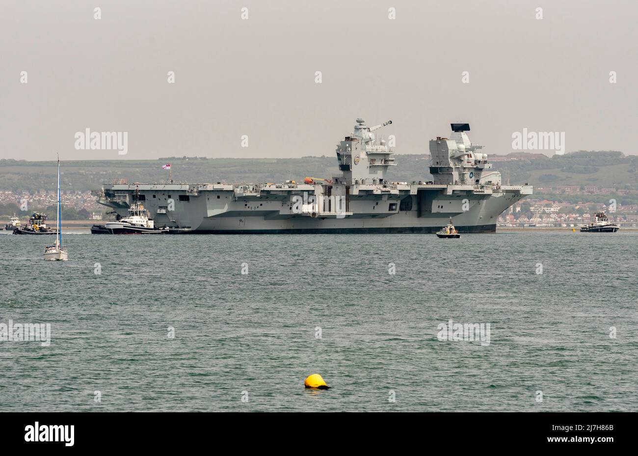 Port Portsmouth, Hampshire, England, UK. 2022. Tugs in attendace to rotate the aircraft carrier HMS Prince Charles in Portsmouth Harbour UK. Stock Photo