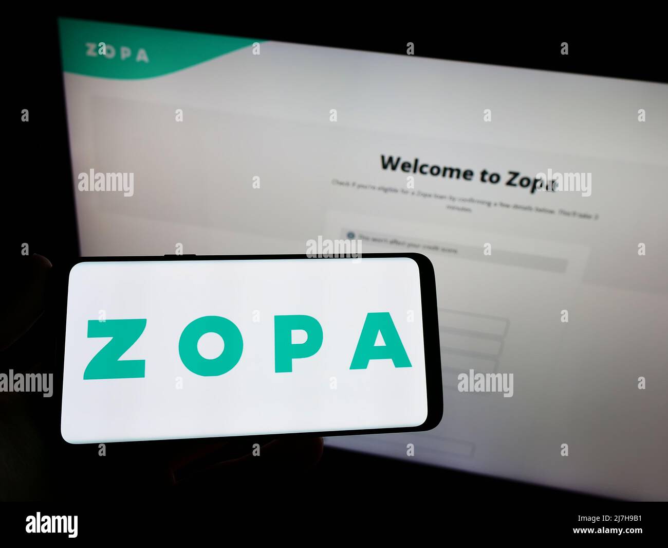Azopa Screen Person holding smartphone with logo of British fintech company Zopa ...