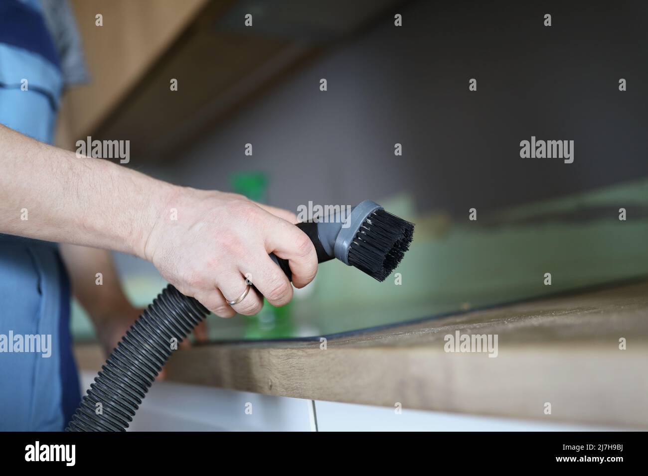 Male worker remove dust with vacuum cleaner, nozzle on cleaning device Stock Photo