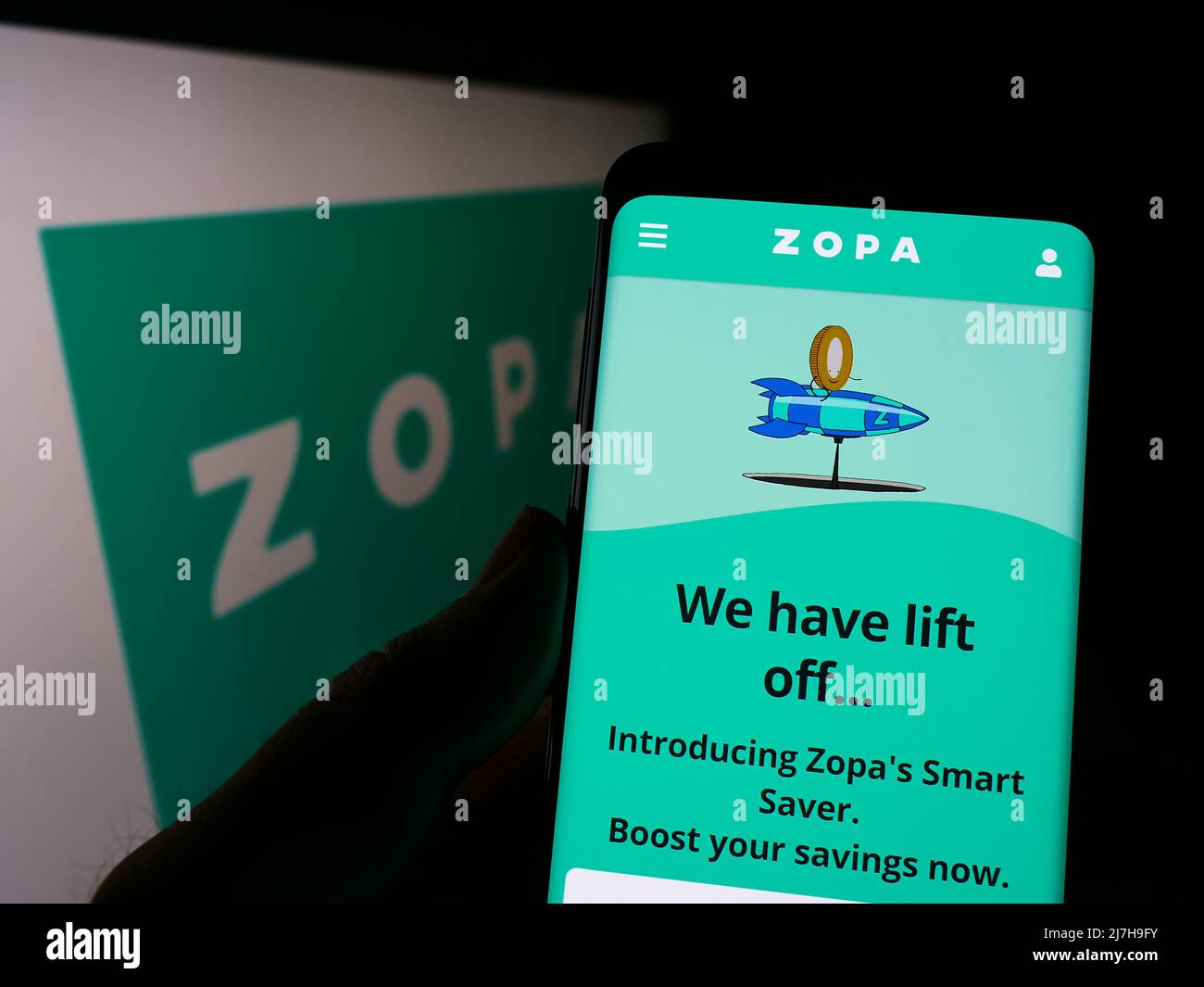 Azopa Screen Person holding cellphone with webpage of British fintech company Zopa ...