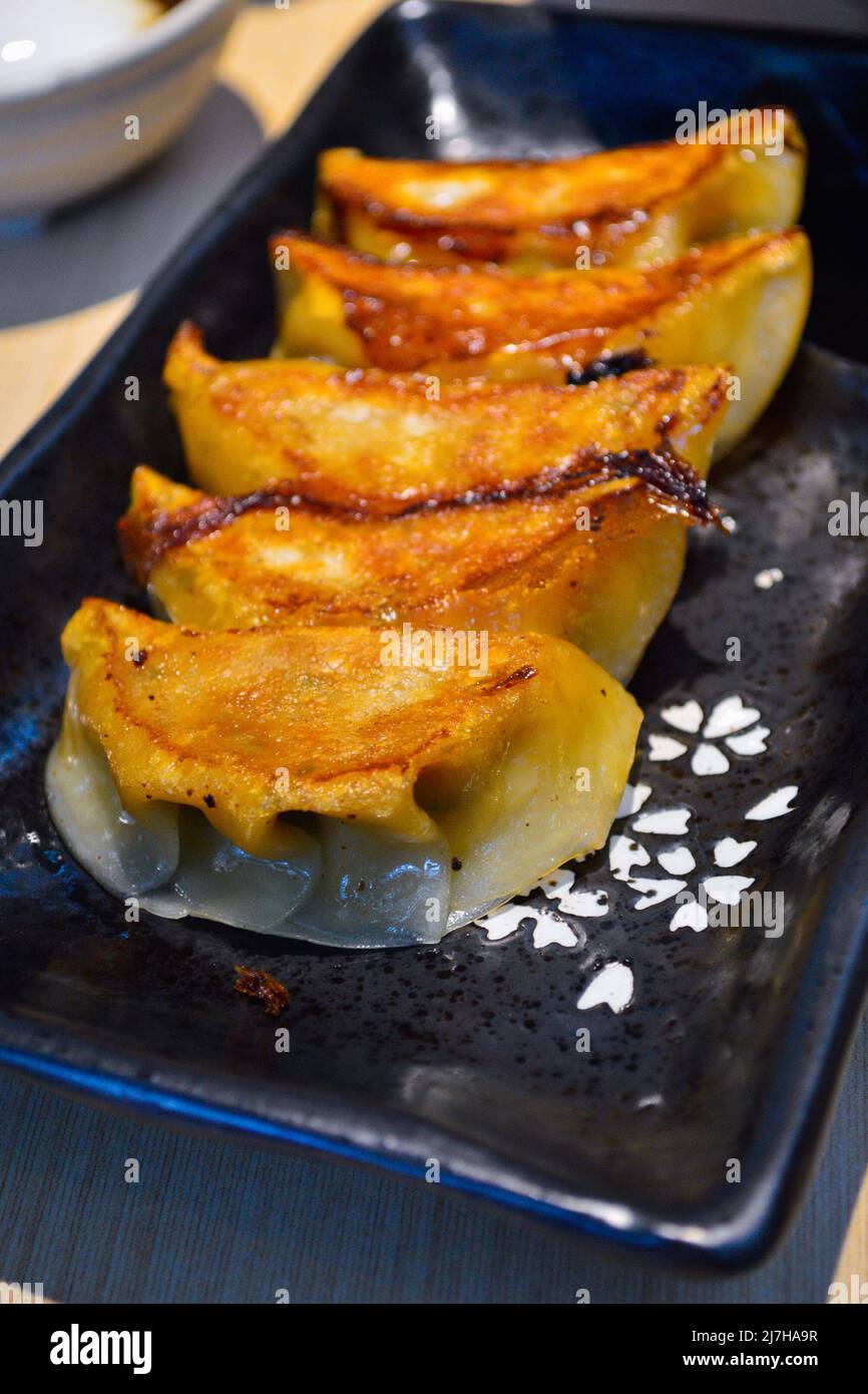 Closeup of Japanese style fried gyoza (dumplings) in a black plate. Authentic shot at restaurant. Stock Photo