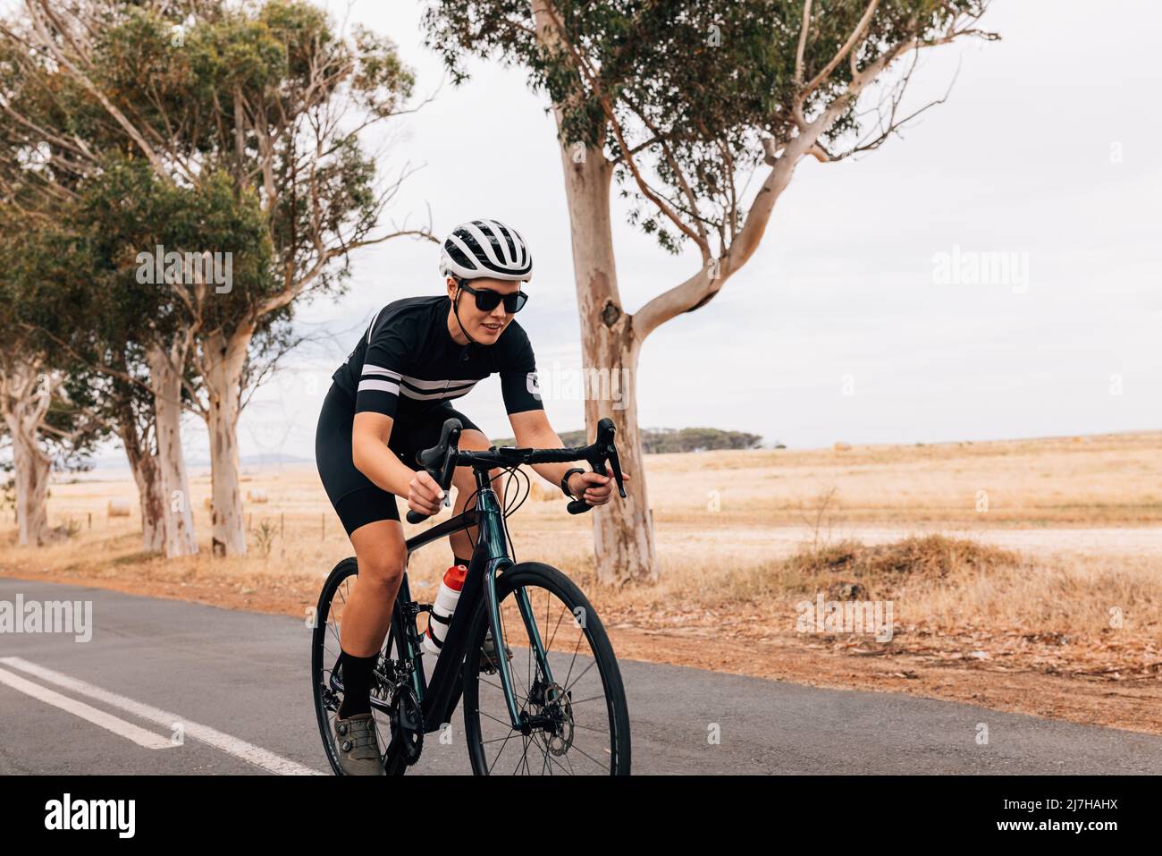 Female cyclist riding her pro bike fast on country road Stock Photo - Alamy