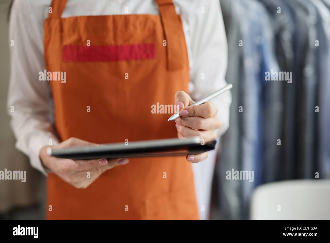 Dry cleaning company worker in uniform, girl hold tablet device with