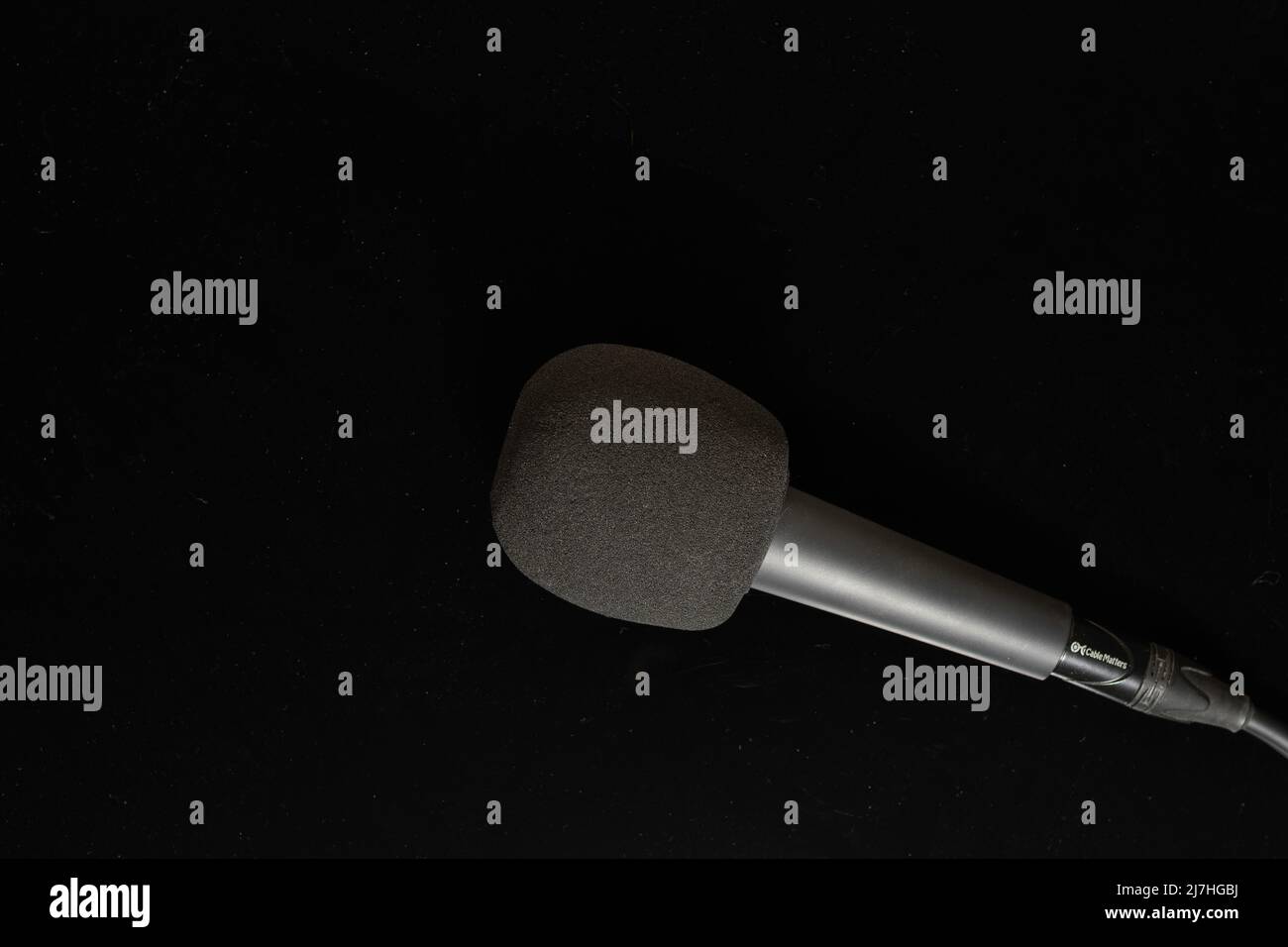 Hand held microphone with foam pop filter isolated on black background Stock Photo