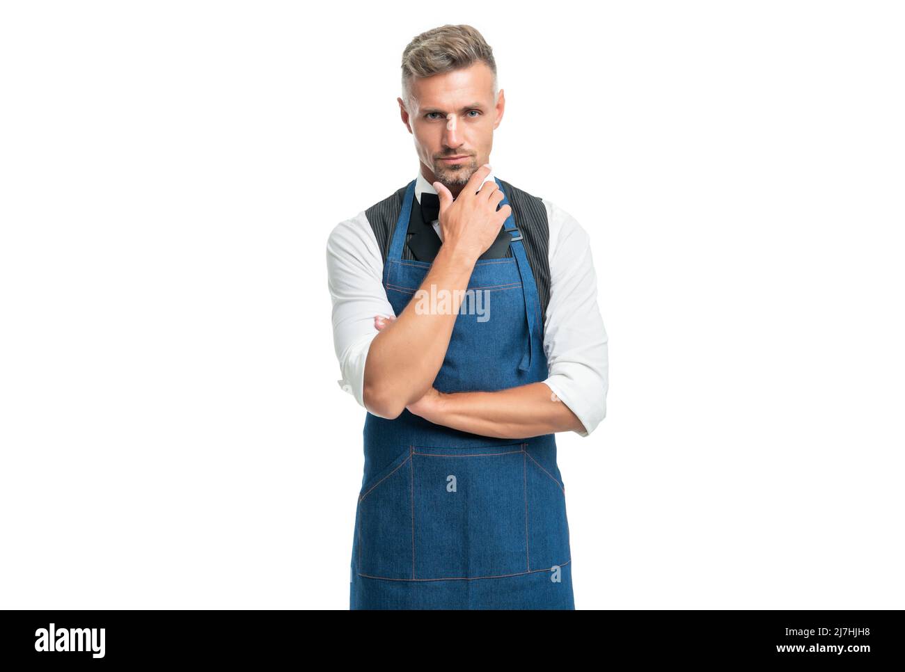Serious barman in bow and bartender apron stroking chin isolated on white Stock Photo