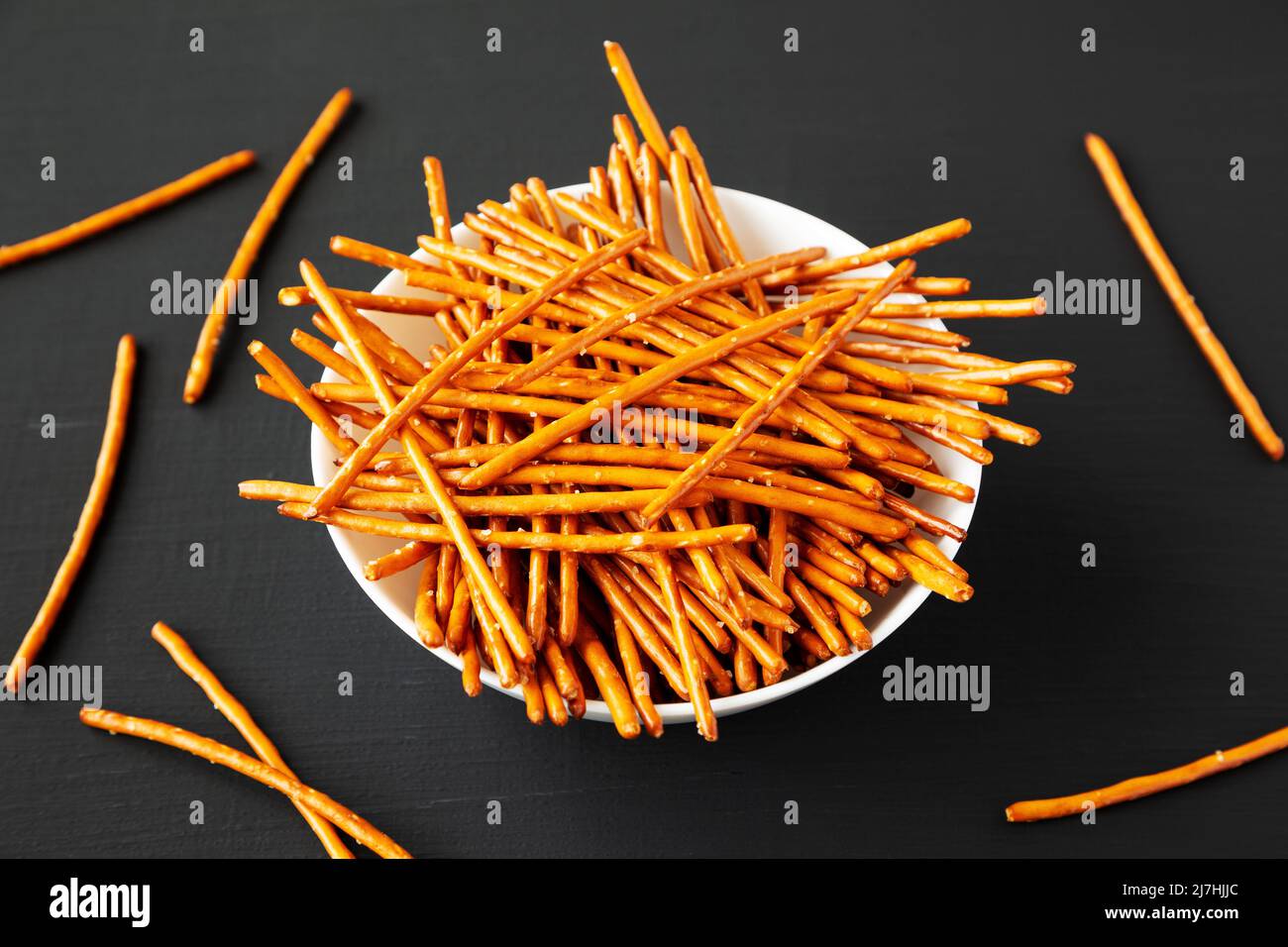 Crunchy Salty Baked Pretzel Sticks in a Bowl on a black background, side view. Stock Photo
