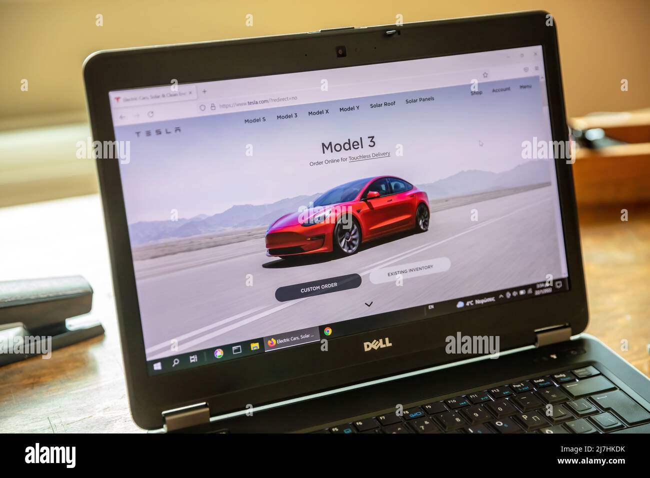 Greece, Athens, January 23 2022. TESLA CAR SELECTION. Ad, online red Tesla model 3 electric auto. Computer laptop on wooden table, close up view Stock Photo