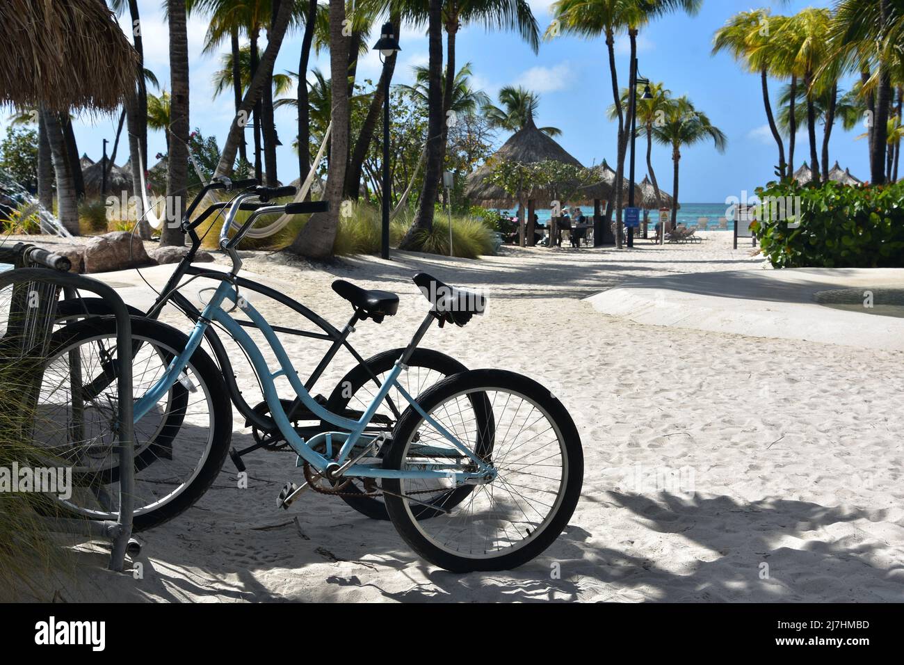 Two electric bikes parked in the sand on a beach in Aruba Stock Photo