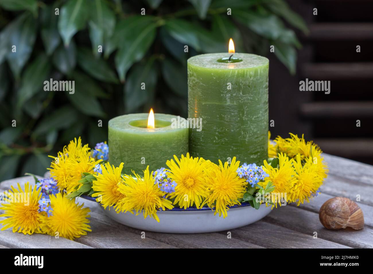 decoration with candles and wreath of dandelions and forget me not flowers Stock Photo