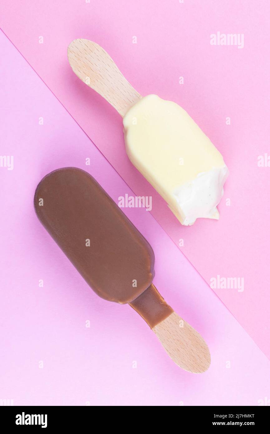 Ice cream on stick vanilla and chocolate. Two ice cream bars on a wooden stick top view flat lay summer concept on pink background Stock Photo