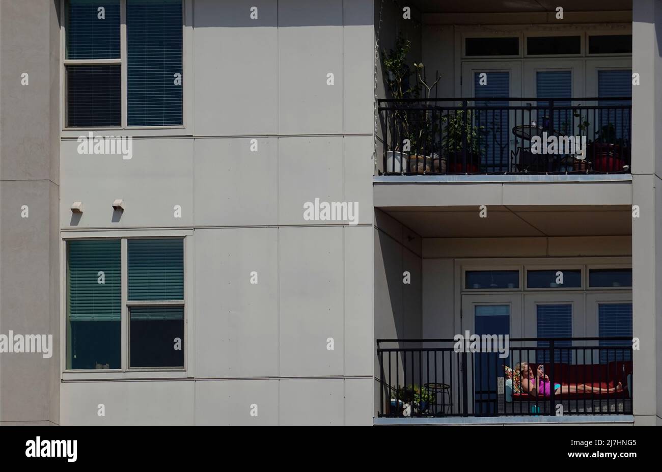 woman sitting on apartment balcony using her cell phone in Greenville SC Stock Photo