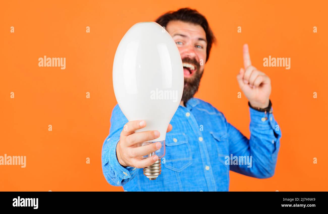 Good idea. Smiling man with light bulb pointing finger up. Energy and electricity. Lightbulb in hand. Stock Photo