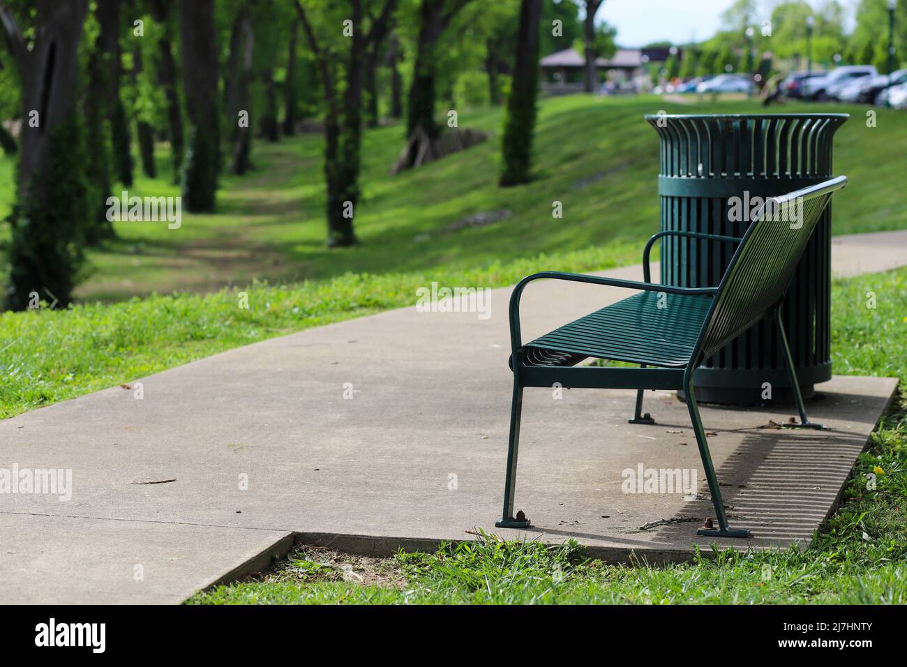 A green metal park bench in a park in the summer Stock Photo