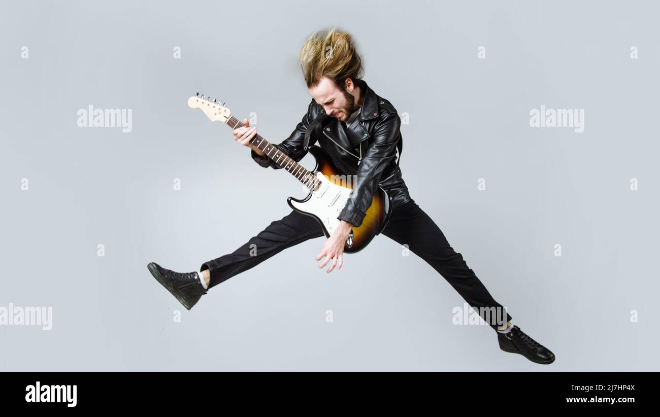 Brutal bearded man jumping with electric guitar. Rock musician. Heavy metal player. Music star. Stock Photo