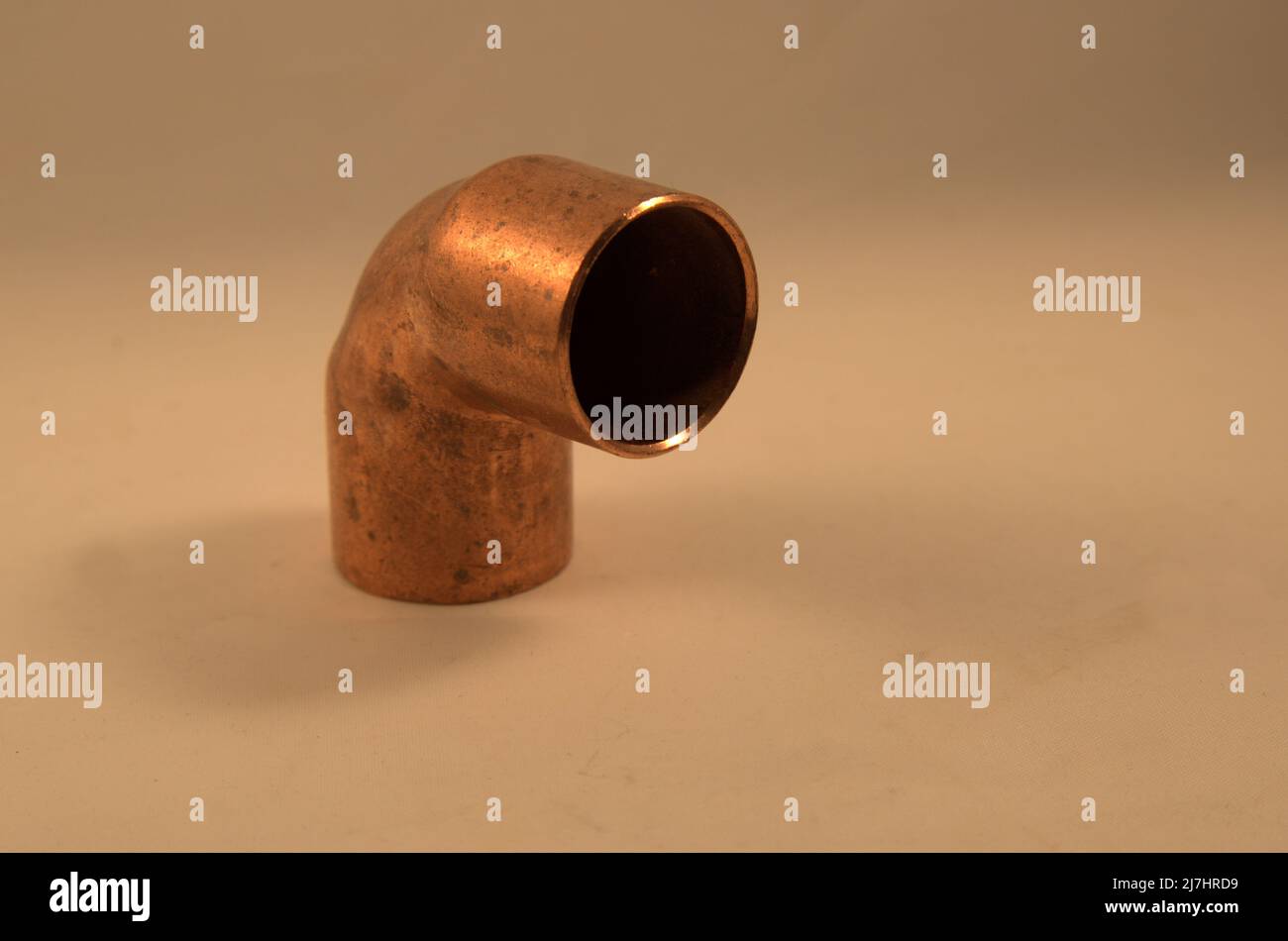 copper pipe elbow joint on tan background Stock Photo Alamy