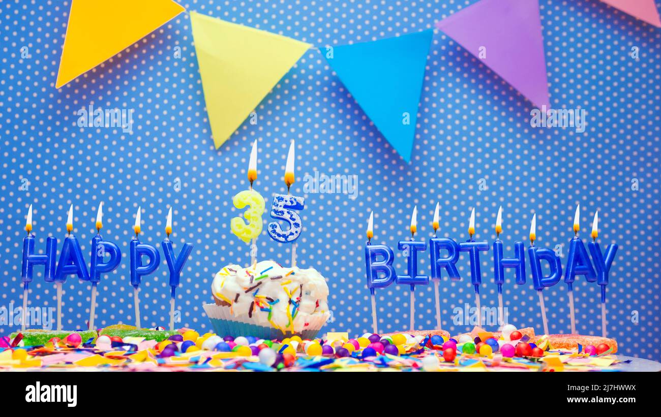 Happy birthday candle letters with a number or digit on a beautiful blue background. Copy space