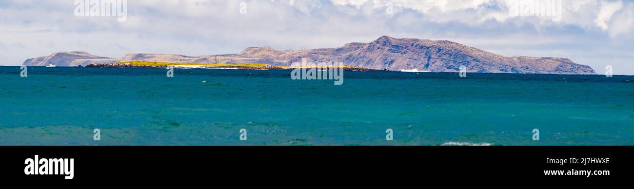 A small island in front of Academy Bay off the island of Santa Cruz, with Santa Fe Island in the background, Galapagos Archipelago, Ecuador. Four imag Stock Photo
