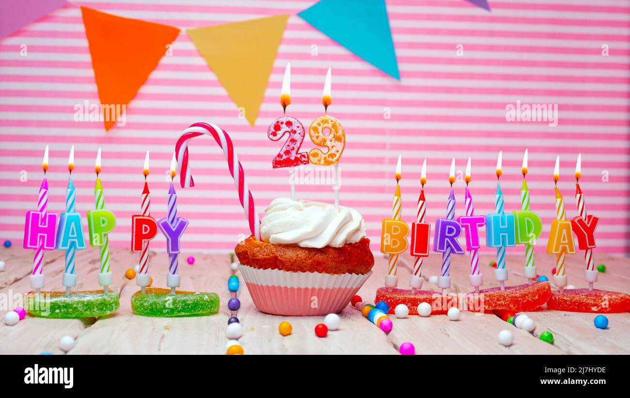 Happy birthday card on a pink background, with a figure in a cupcake. Beautiful happy birthday background with a number with a burning candle. Festive Stock Photo