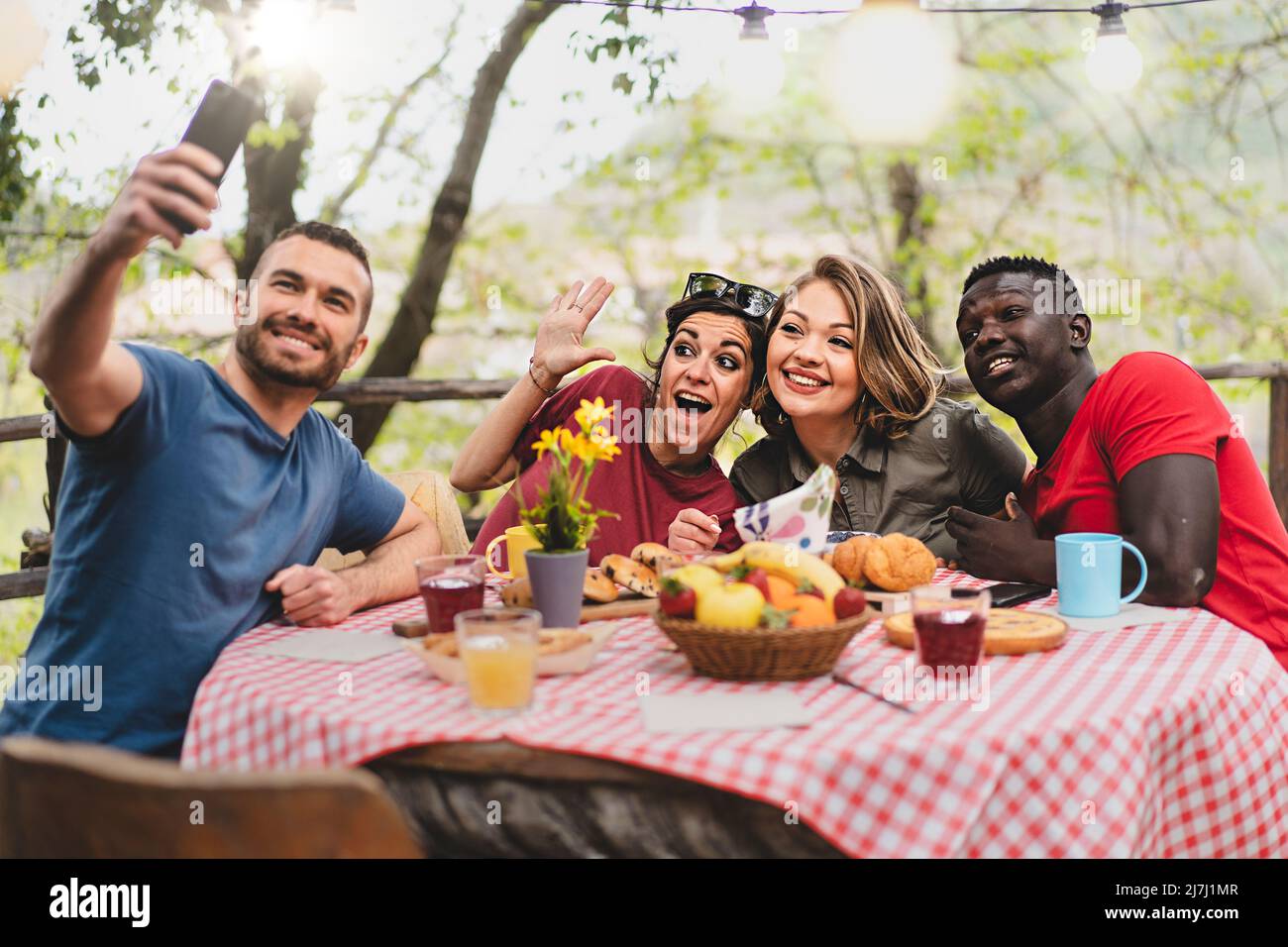 Multiracial friends relaxing taking selfie at picnic table - Young ...