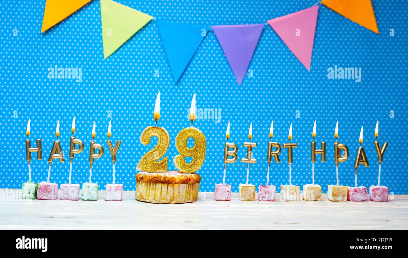 Happy birthday from candle letters on a blue background with white polka dot copy space. Happy birthday cupcake with burning golden candle Stock Photo
