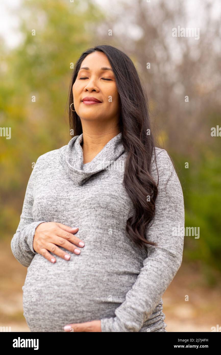 Happy Asian pregnant woman holding her stomach Stock Photo - Alamy