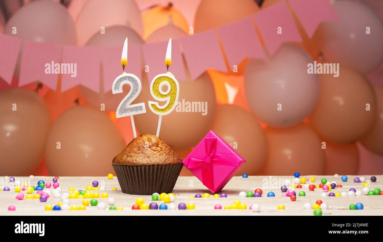 Balloon decorations and a happy birthday candle with a number in a cake. Happy birthday greetings in pink colors for a girl, copy space. Muffin Stock Photo