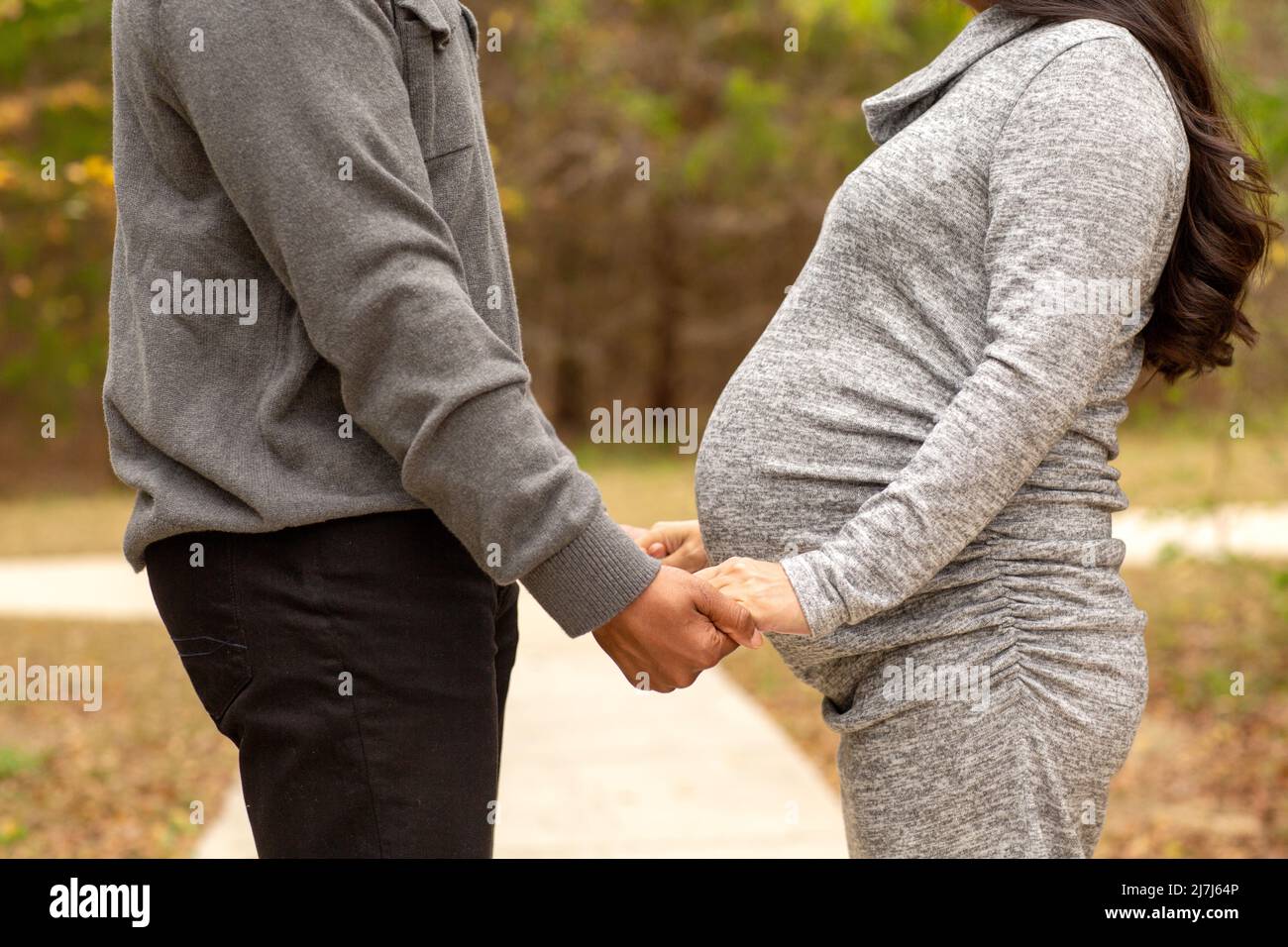Expecting Couple Holding Hands At The Park Stock Photo