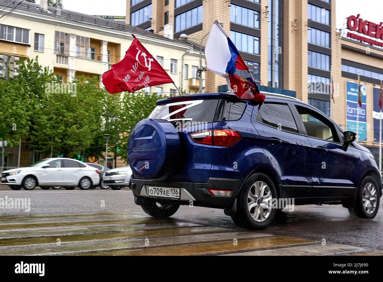 Voronezh, Russia, 09/05/2022, A car with the Soviet flag, the Russian national flag and the symbol of military aggression 'Z' on the 77th anniversary of the Victory Day in Voronezh. Victory Day in Russia has long turned from a day of memory of the feat of the Soviet people into a day of oblivion, from a day of victory over Nazi aggression into a day of saber-rattling, from a day of the triumph of reason and progress into a day of obscurantism and idiocy. People dress up children in Soviet uniforms, arrange a carnival, get drunk, brandish various symbols: from communist to nationalist and monar Stock Photo