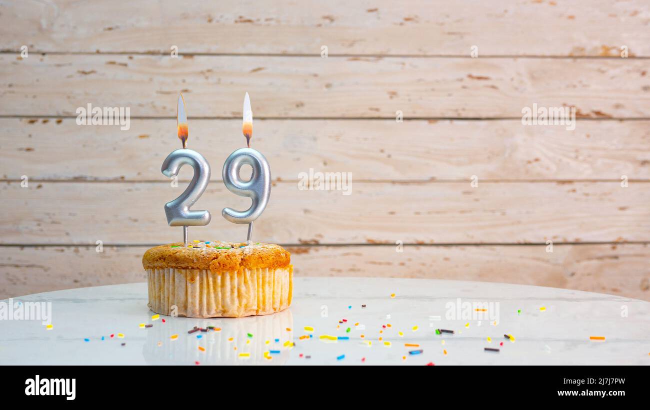Happy birthday silver digits on white boards background copy space. Beautiful birthday card with a cupcake with a burning candle Stock Photo