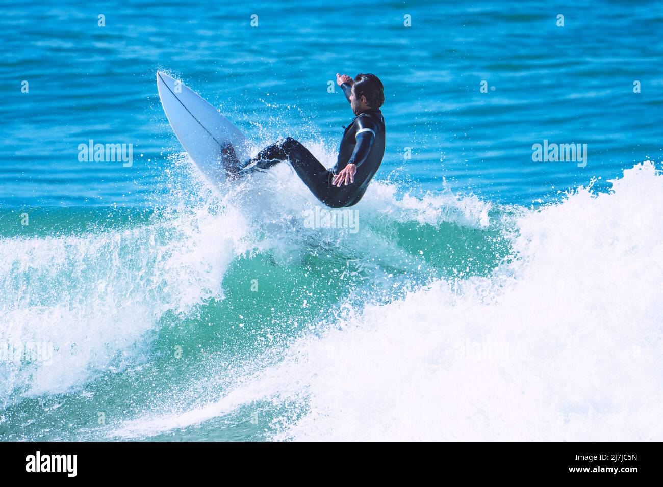 Surfer making trick on the wave on shortboard. Man catching waves in ocean. Water sports activity Stock Photo