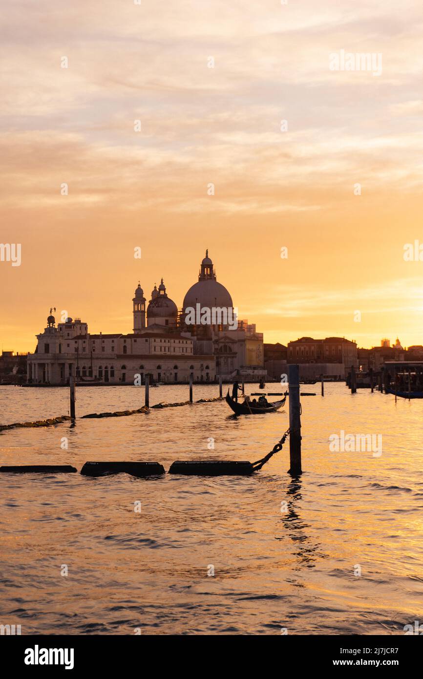 Sunset in Venice, Italy with silhouette of a gondola and basilica in the background Stock Photo