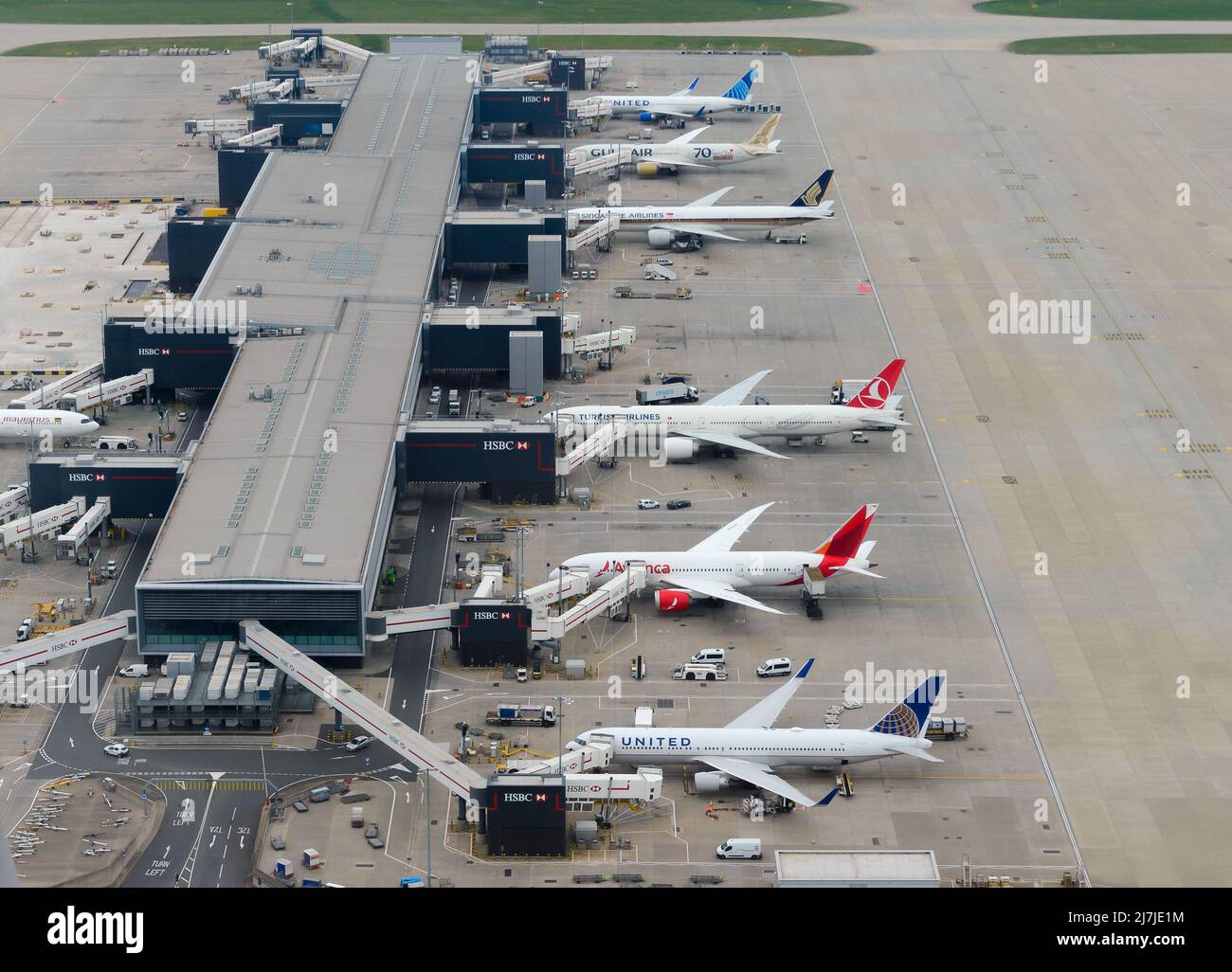 Heathrow Airport Terminal 2 aerial view, also know as The Queen's Terminal. Busy airport terminal in United Kingdom with multiple aircraft. Stock Photo