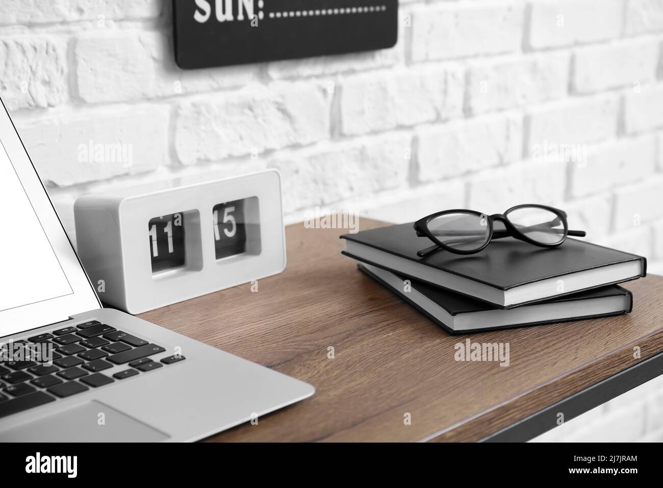 Alarm clock, notebooks, eyeglasses and laptop on wooden table near white  brick wall, closeup Stock Photo - Alamy