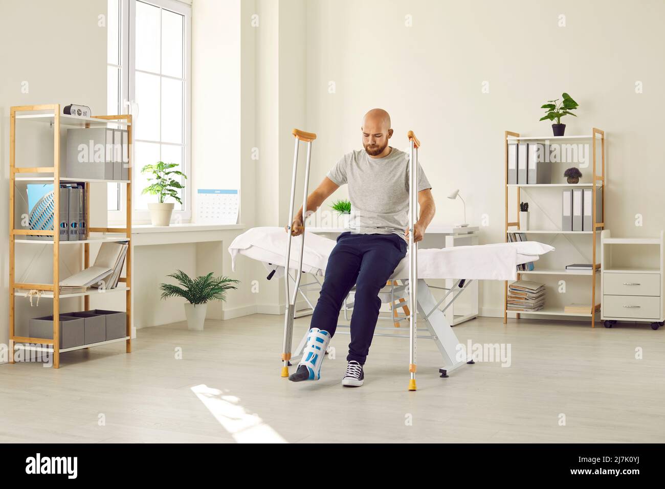 Patient with foot injury wearing support brace and trying to stand up