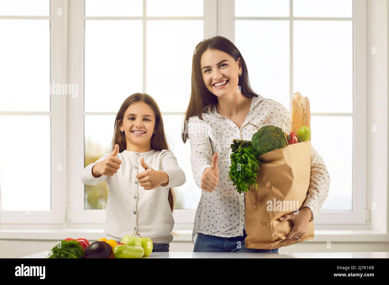 Healthy eco friendly family showing thumbs up holding grocery bag with fresh organic vegetables. Stock Photo