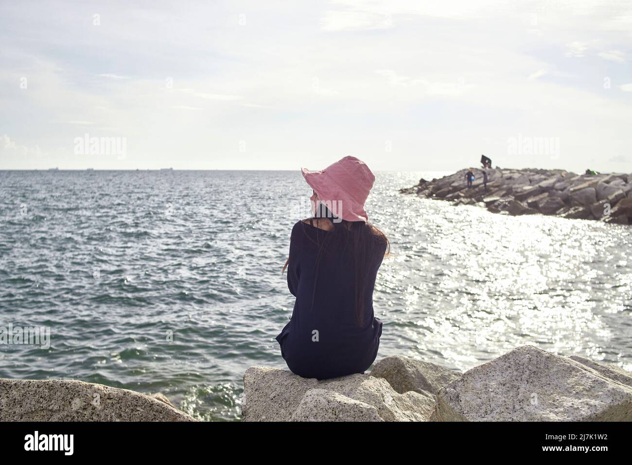 A woman sitting on rocky beach Stock Photo Alamy