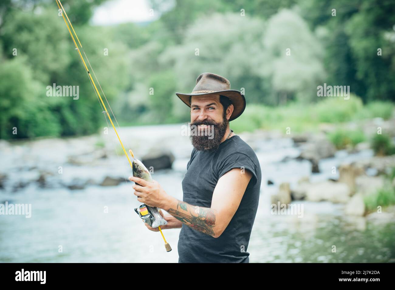 Fisherman man on river or lake with fishing rod. Hipster bearded man ...
