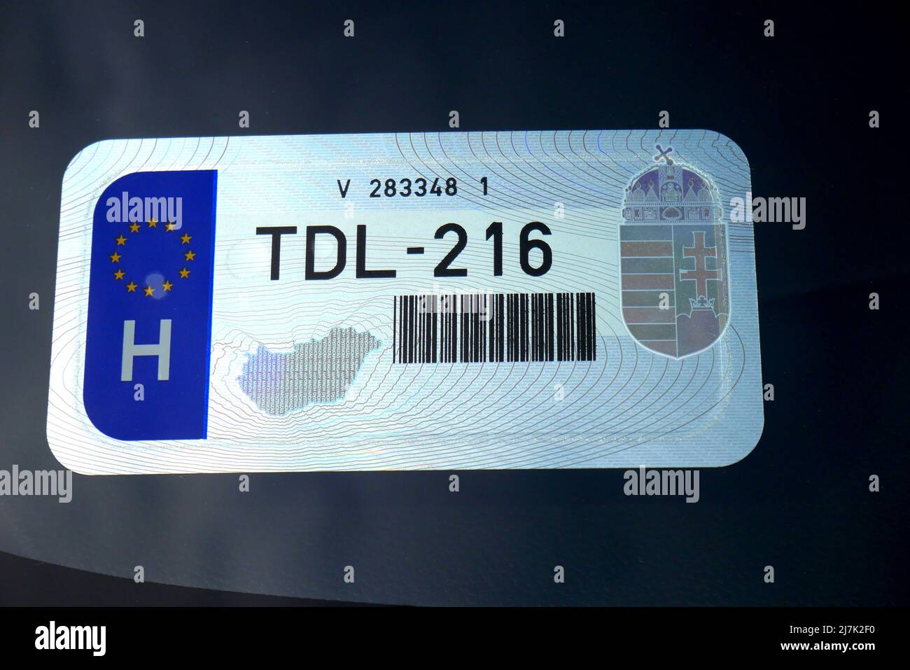 Vehicle registration sticker on a car windscreen in Hungary, with a bar