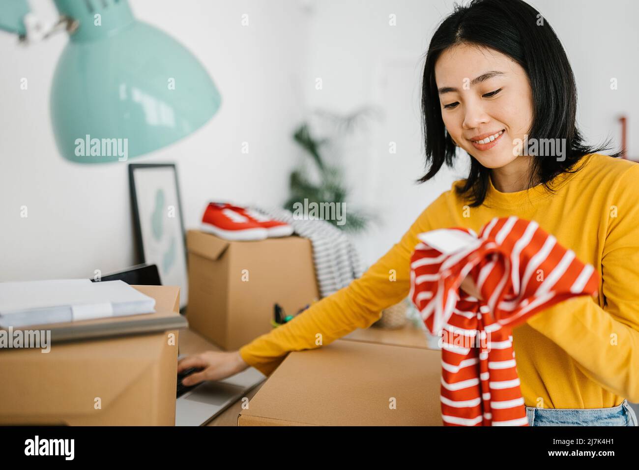 Female young small business owner selling clothes online while working at home. Stock Photo