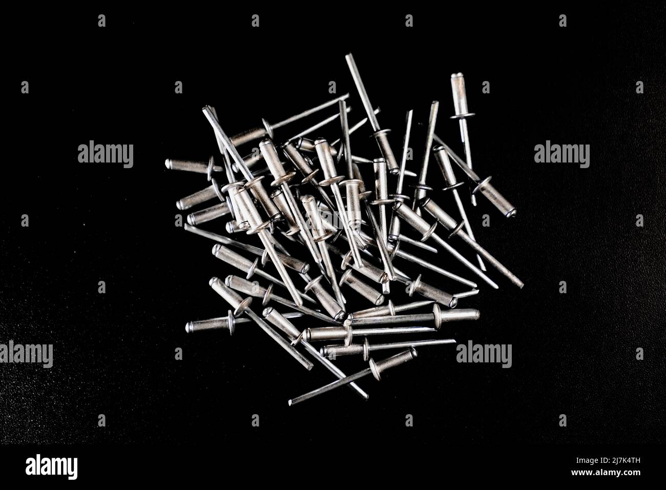 rivet nails arranged in messy composition on black background Stock Photo