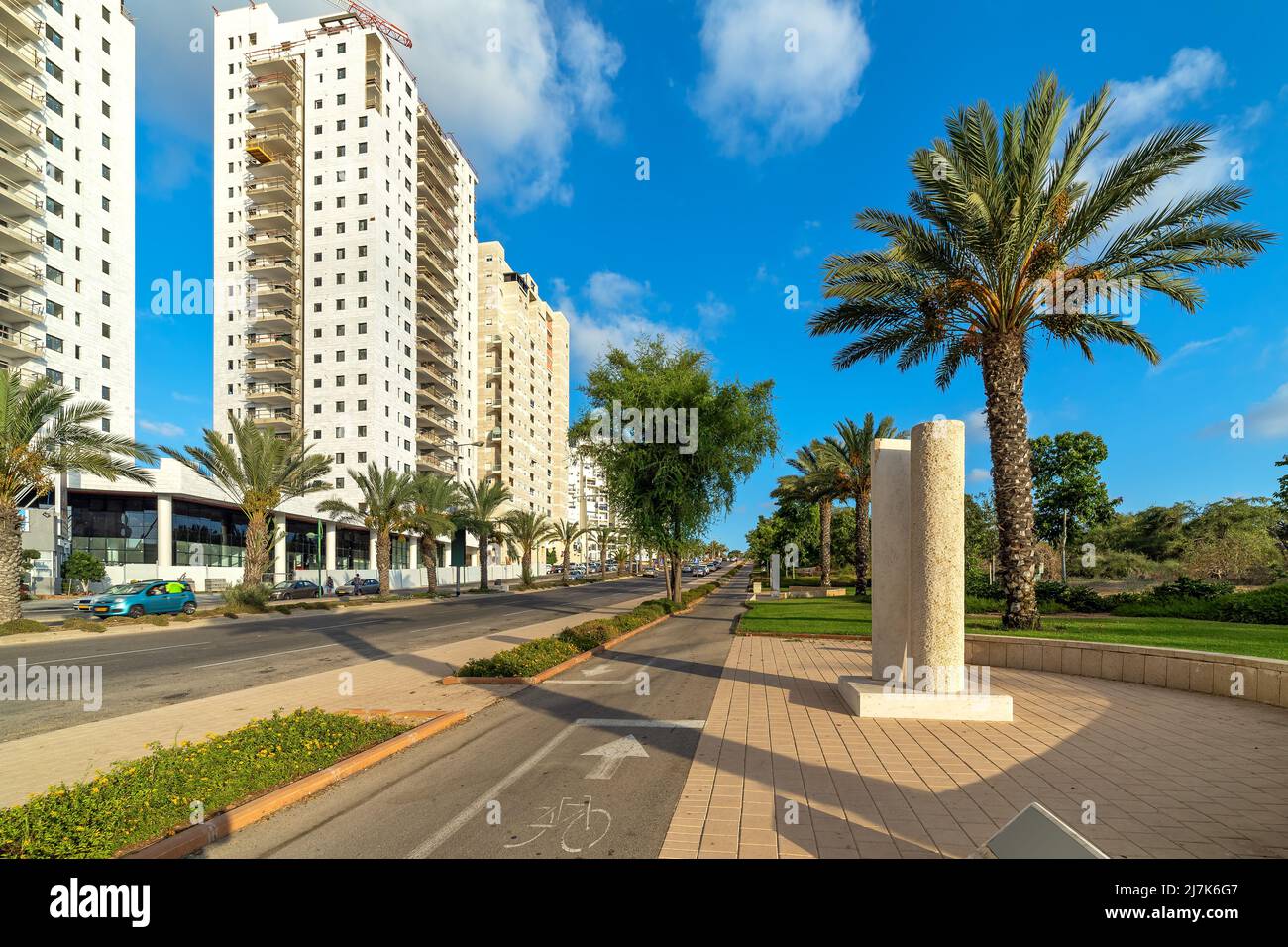 Sidewalk and urban road along multistory residential buildings under blue sky in Ashkelon, Israel. Stock Photo