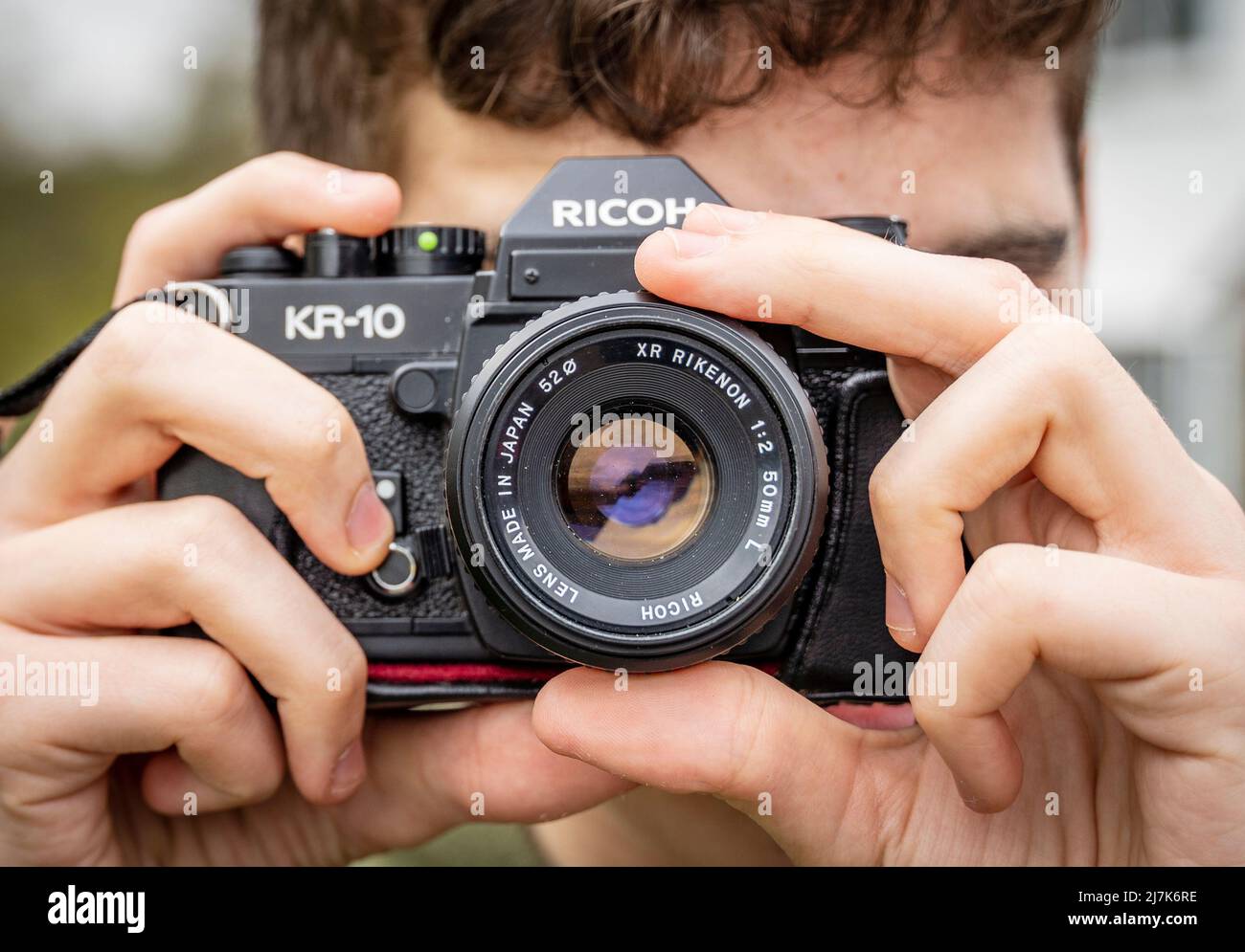 Close-up shot of a man focusing a vintage Ricoh KR-10 SLR camera Stock Photo
