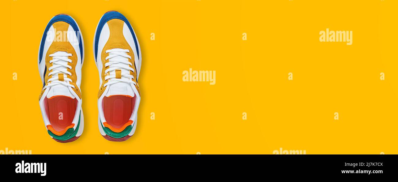 Pair of trendy colorful shoes on yellow background, flat lay top view. Sport sneakers with copy space, Summer footwear concept Stock Photo