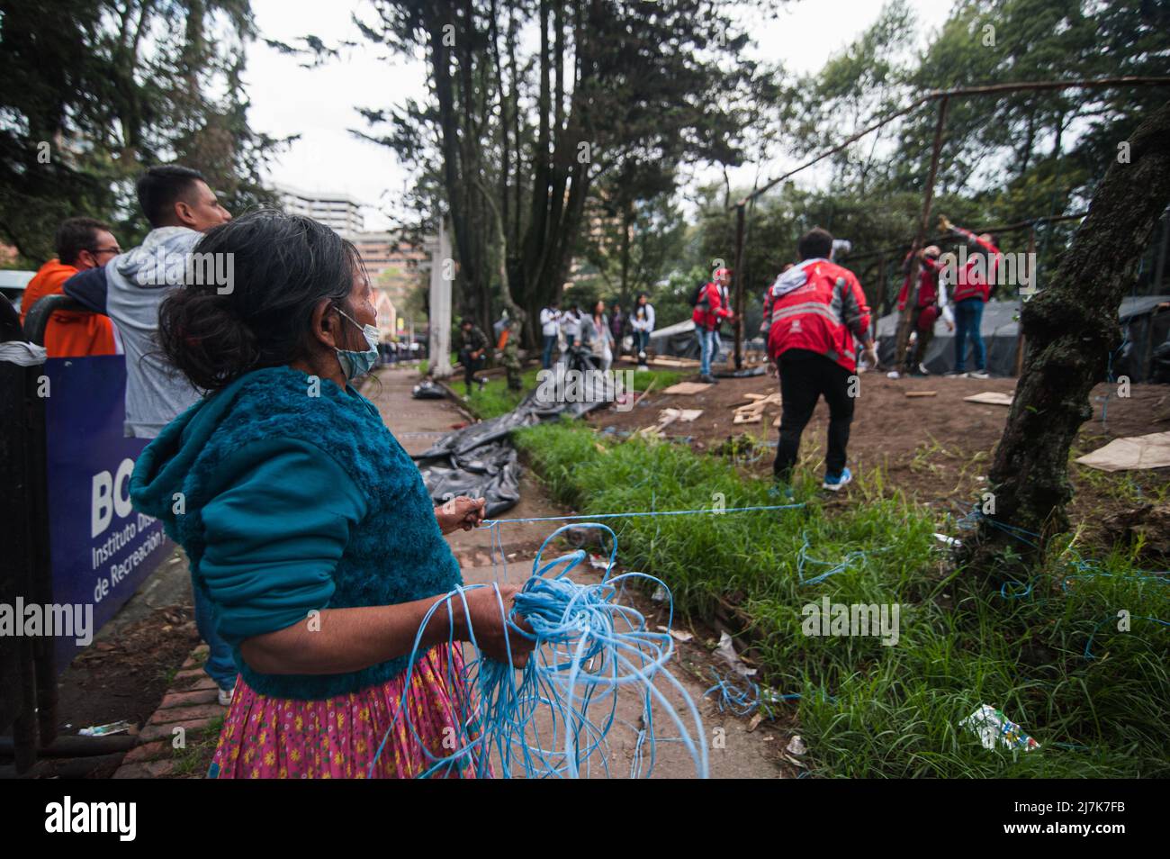 An Embera Indigenous mother helps members of Bogota's social office to dismantle a shed as Embera indigenous communities start leaving the makeshift c Stock Photo